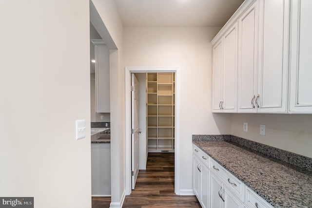 kitchen featuring white cabinets, dark stone counters, and dark hardwood / wood-style floors