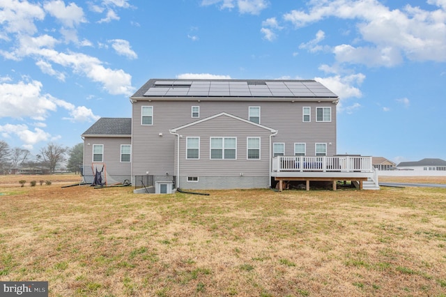 back of house featuring solar panels, a deck, and a yard