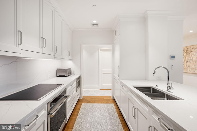 kitchen with stainless steel appliances, light stone countertops, sink, and white cabinets