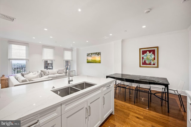 kitchen with sink, crown molding, light stone countertops, light hardwood / wood-style floors, and white cabinets