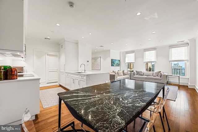 dining room with ornamental molding, sink, and light hardwood / wood-style floors