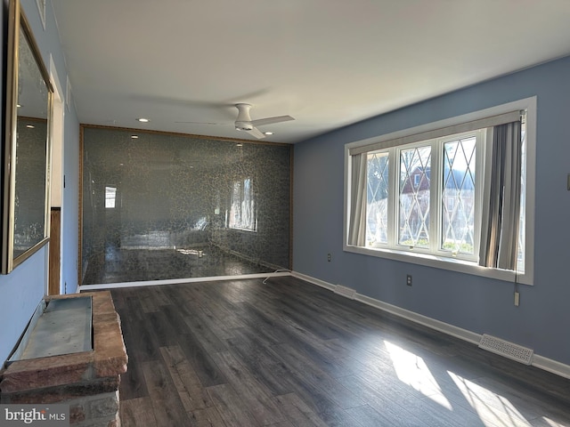 empty room with ceiling fan and dark hardwood / wood-style flooring