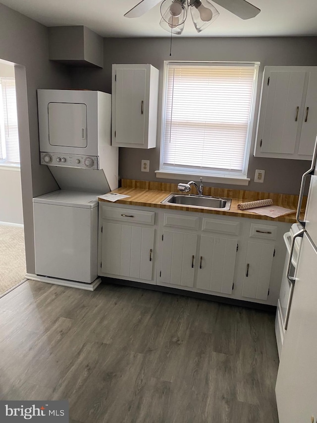 washroom featuring dark hardwood / wood-style flooring, sink, and stacked washer and clothes dryer