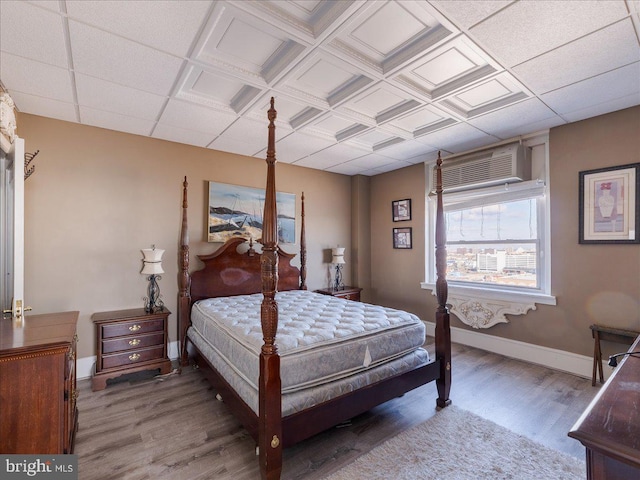 bedroom with a wall mounted air conditioner and hardwood / wood-style flooring