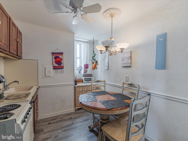 dining area featuring ceiling fan with notable chandelier, dark hardwood / wood-style flooring, and sink