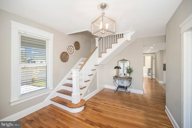 stairway with wood-type flooring and a notable chandelier