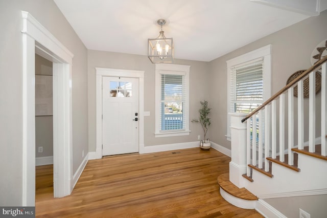 entrance foyer with hardwood / wood-style floors and a notable chandelier