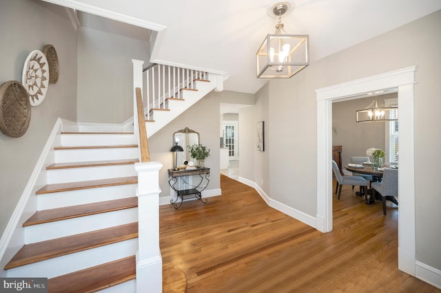 stairway featuring hardwood / wood-style flooring, an inviting chandelier, and a wealth of natural light