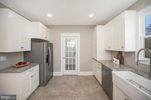 kitchen with white cabinets, sink, light stone countertops, light tile patterned floors, and stainless steel appliances