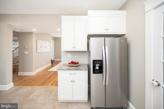 kitchen featuring white cabinetry, stainless steel fridge, light stone countertops, and light wood-type flooring