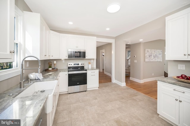 kitchen with white cabinetry, light stone countertops, light wood-type flooring, and appliances with stainless steel finishes