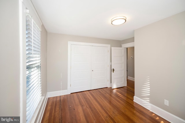 unfurnished bedroom with a closet and dark wood-type flooring