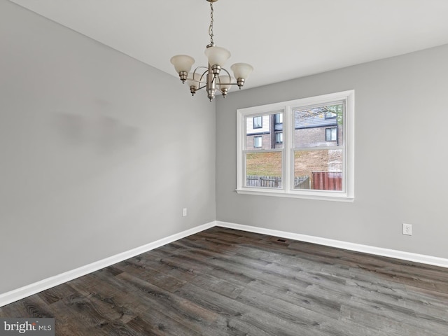 empty room featuring dark wood-type flooring and an inviting chandelier