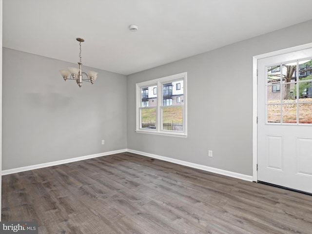 unfurnished dining area with a chandelier, a wealth of natural light, and dark wood-type flooring