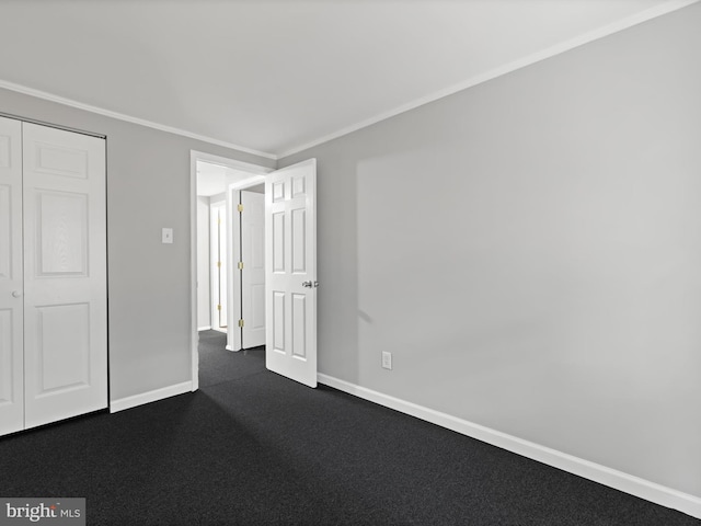 unfurnished bedroom with dark colored carpet, ornamental molding, and a closet