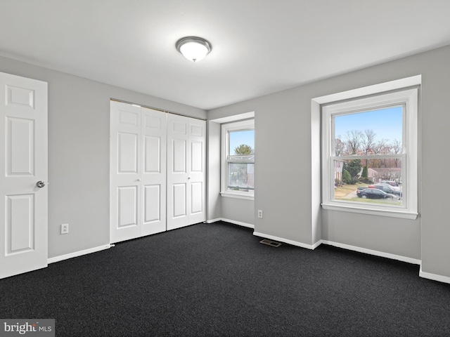 unfurnished bedroom featuring a closet and dark carpet