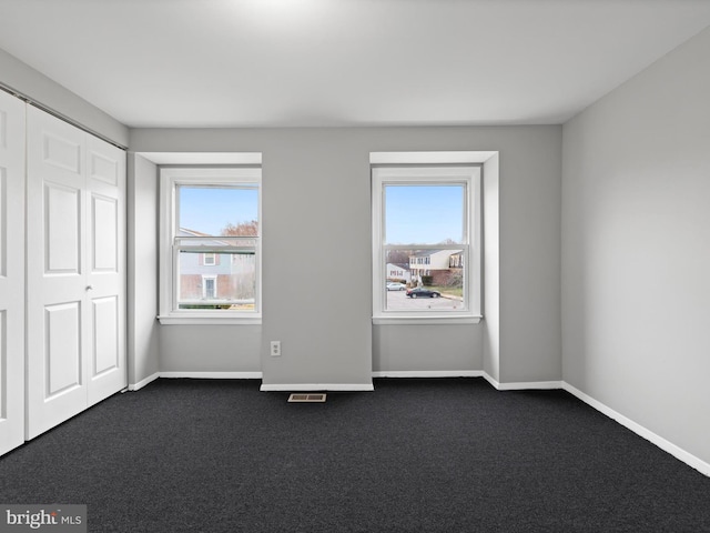 unfurnished bedroom with dark carpet and a closet