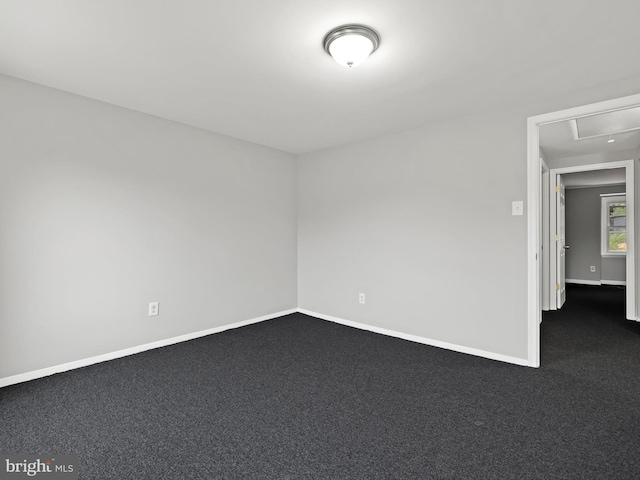 spare room with dark colored carpet