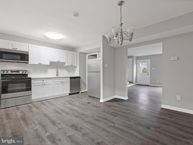 kitchen with appliances with stainless steel finishes, wood-type flooring, decorative light fixtures, a notable chandelier, and white cabinets