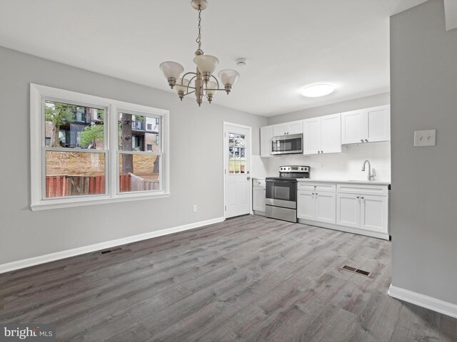 kitchen featuring white cabinetry, wood-type flooring, hanging light fixtures, and appliances with stainless steel finishes