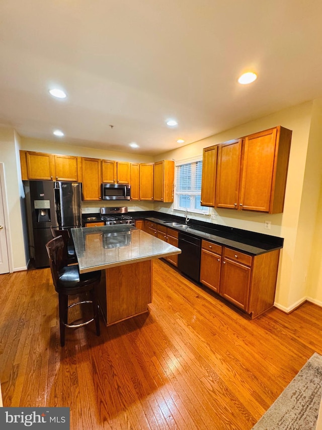 kitchen featuring appliances with stainless steel finishes, sink, light hardwood / wood-style flooring, a kitchen island, and a breakfast bar area