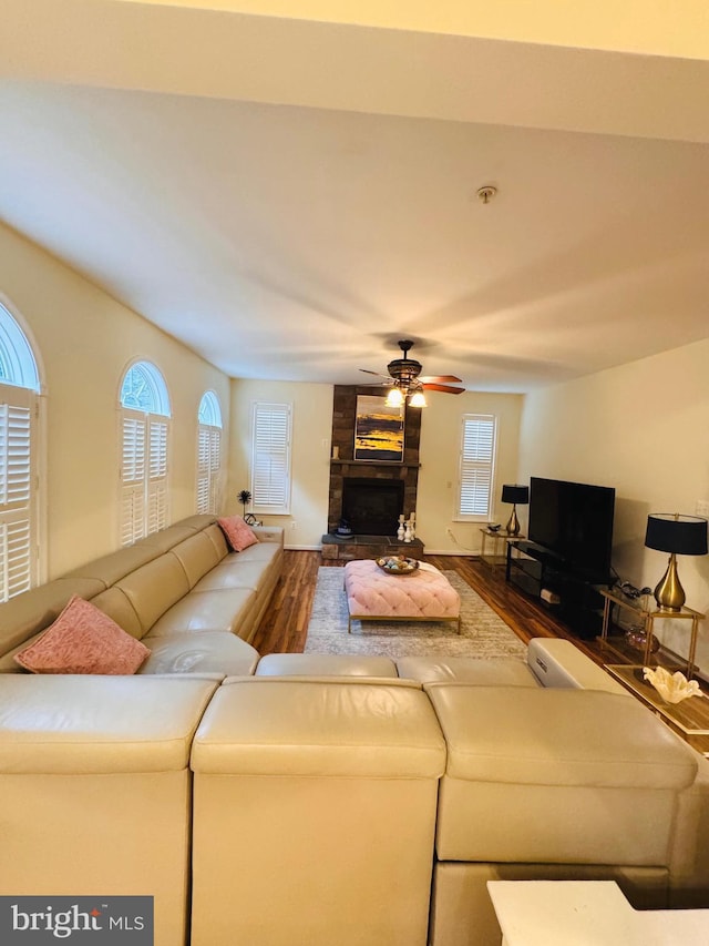 living room with hardwood / wood-style floors, ceiling fan, and a large fireplace