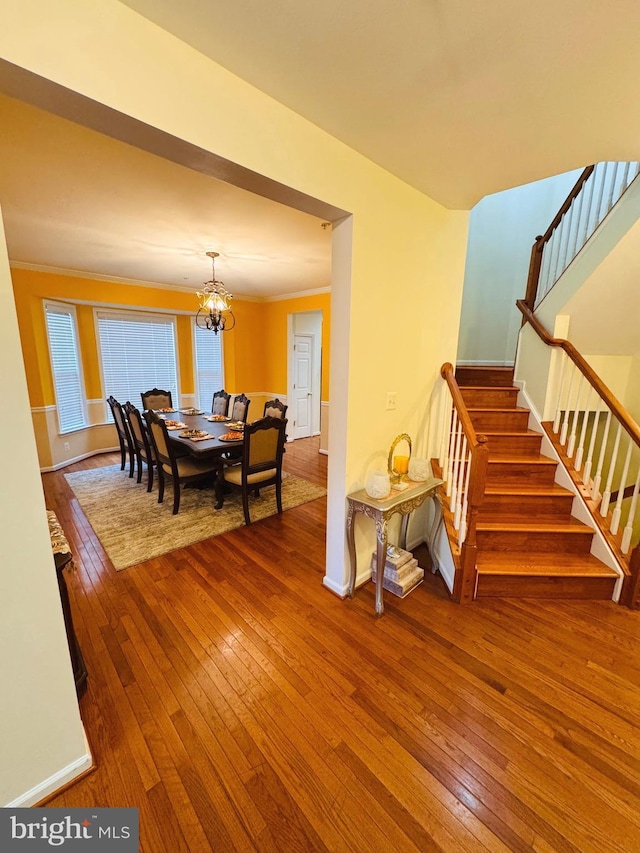 dining area featuring a notable chandelier, wood-type flooring, and ornamental molding