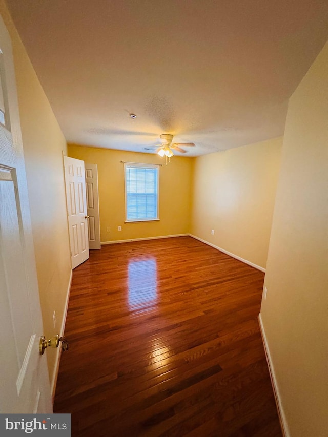 unfurnished room with ceiling fan and dark wood-type flooring