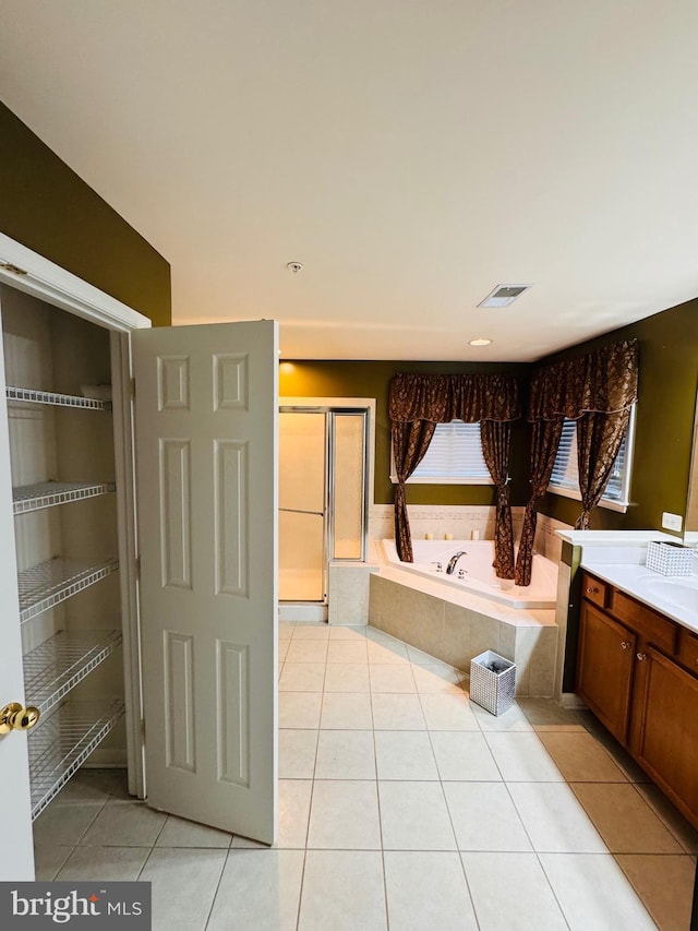 bathroom with tile patterned flooring, a relaxing tiled tub, and vanity