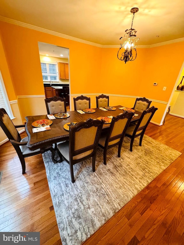 dining area featuring a notable chandelier, light wood-type flooring, and ornamental molding