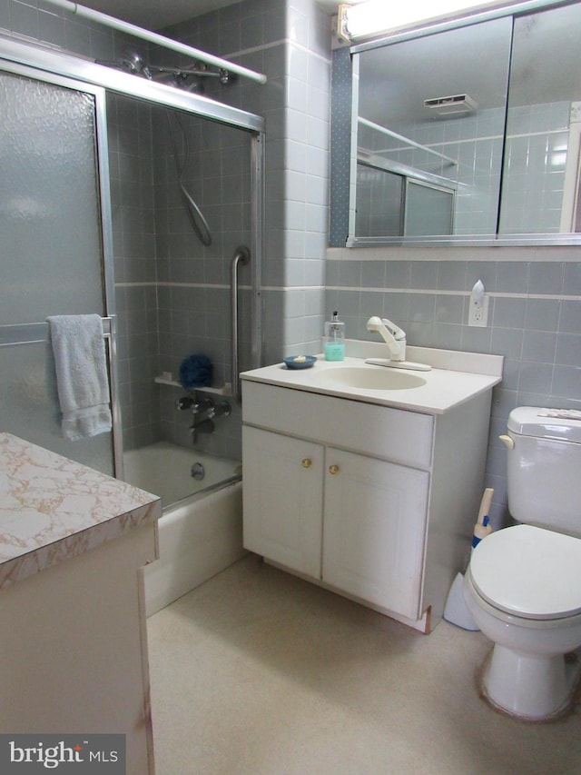 full bathroom featuring vanity, backsplash, bath / shower combo with glass door, toilet, and tile walls