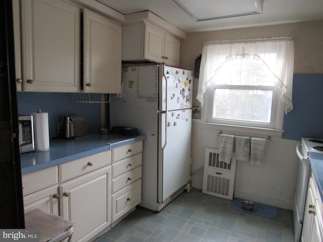 kitchen with white cabinets, white appliances, and radiator