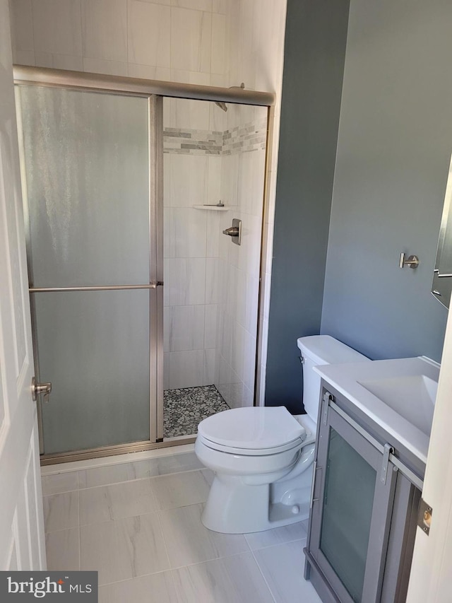 bathroom featuring tile patterned floors, vanity, toilet, and a shower with door