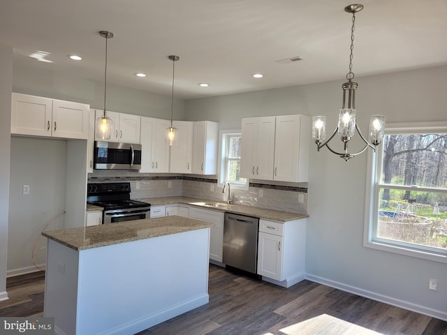 kitchen featuring pendant lighting, stainless steel appliances, and white cabinetry