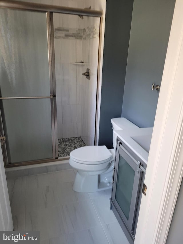 bathroom with vanity, toilet, and a shower with shower door