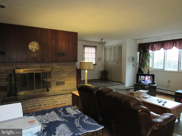 living room featuring a stone fireplace, wooden walls, dark hardwood / wood-style floors, and a baseboard heating unit