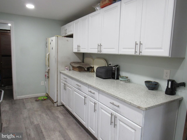 kitchen with light wood-type flooring, white fridge, and white cabinetry