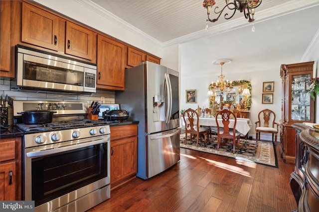 kitchen featuring dark hardwood / wood-style floors, crown molding, stainless steel appliances, and an inviting chandelier