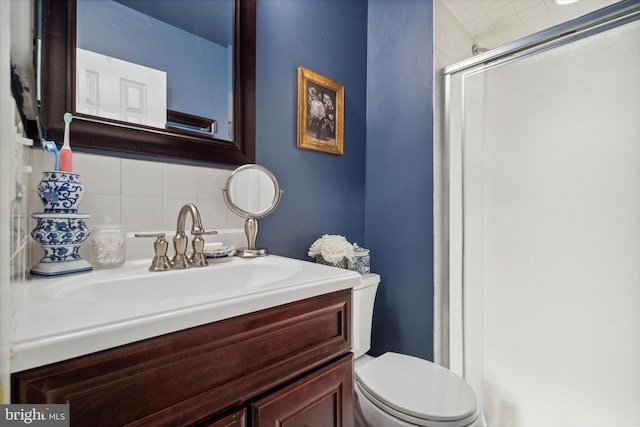 bathroom featuring backsplash, a shower with door, vanity, and toilet