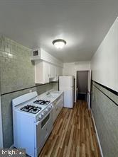 kitchen featuring dark hardwood / wood-style flooring, white appliances, and white cabinetry