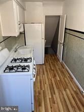 kitchen featuring hardwood / wood-style floors, white cabinetry, white appliances, and sink