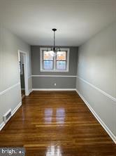 unfurnished dining area with a notable chandelier and dark wood-type flooring