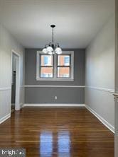 unfurnished dining area featuring dark hardwood / wood-style flooring and a notable chandelier