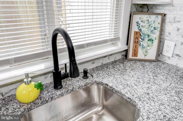 details with decorative backsplash, sink, and light stone countertops