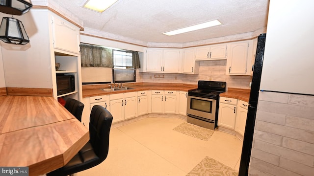 kitchen with a textured ceiling, sink, butcher block counters, and stainless steel range with electric cooktop