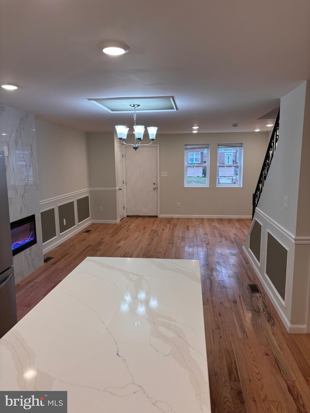 foyer with a premium fireplace, an inviting chandelier, and hardwood / wood-style flooring