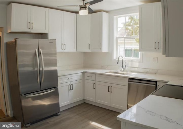 kitchen featuring light stone countertops, stainless steel appliances, sink, light hardwood / wood-style floors, and white cabinetry