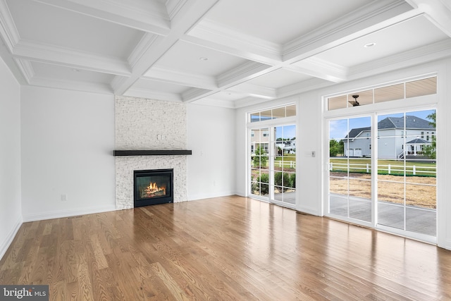 unfurnished living room with beam ceiling, a stone fireplace, hardwood / wood-style floors, and coffered ceiling