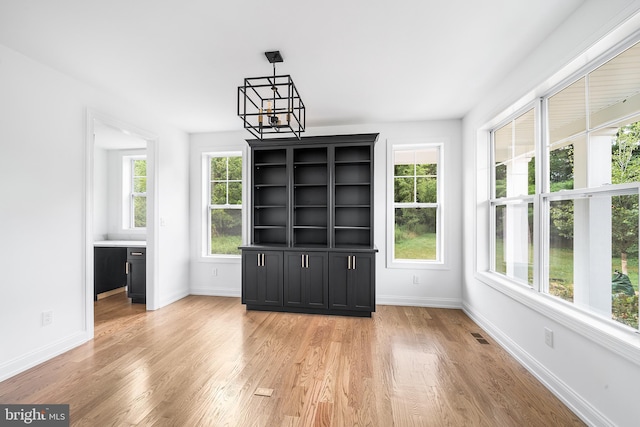 unfurnished dining area with light hardwood / wood-style floors and a notable chandelier