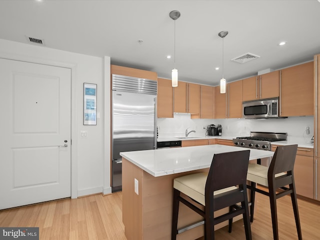 kitchen featuring a sink, appliances with stainless steel finishes, light wood-style flooring, and visible vents